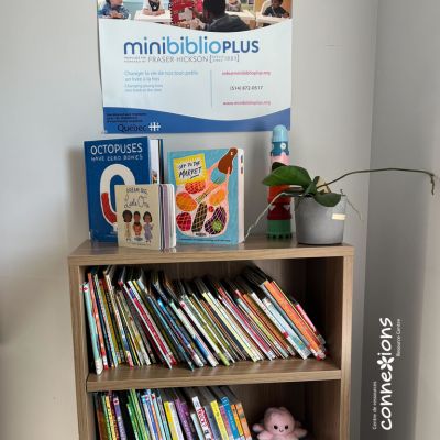 Wooden bookshelf filled with children's books, topped with a sign for minibiblioPLUS