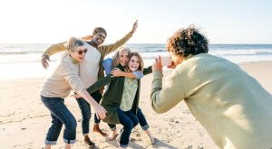 Seniors on the beach having fun as one person takes a picture and 4 others line up.