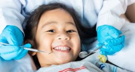 Child smiling as dentist cleans her teeth