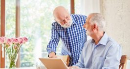 Two men registering for a family doctor on a desktop computer